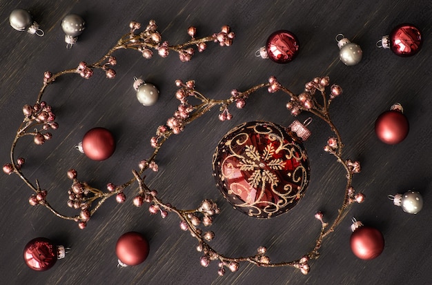 Christmas background with shiny floral garland and festive baubles on dark