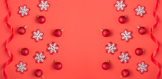 Sfondo di natale con fiocchi di neve, palline rosse e nastro