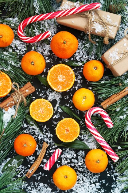 Christmas background with tangerines candies gifts and fir branches on a dark table