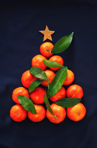 Фото Рождественский фон с мандаринами в форме рождественской елки на темной поверхности