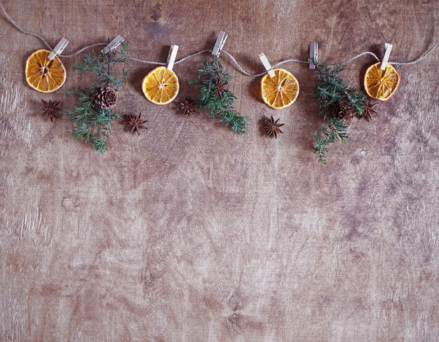 Christmas background with thuja twigs and dried oranges on clothespins on wooden table with copy space