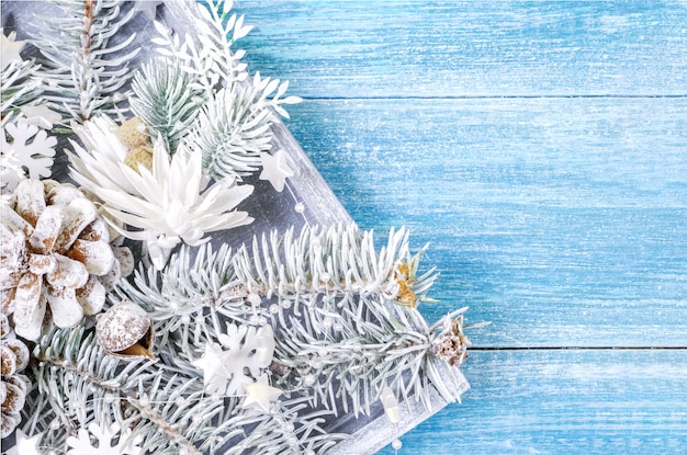 Christmas background with white spruce branches and snowflakes on a blue wooden background