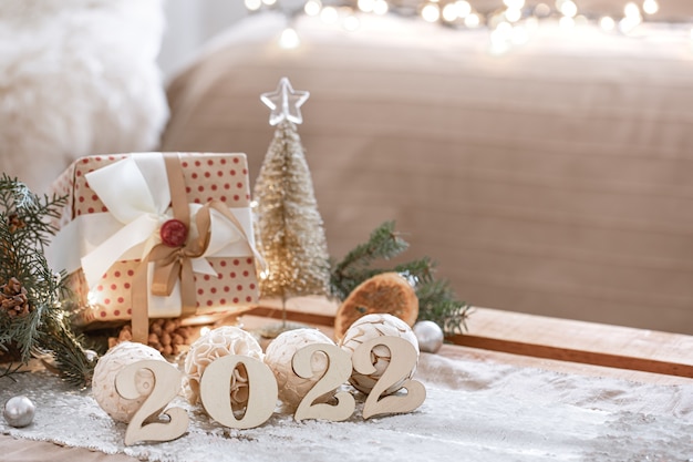 Christmas background with wooden numbers 2022 and decor details on blurred background with bokeh lights, copy space.