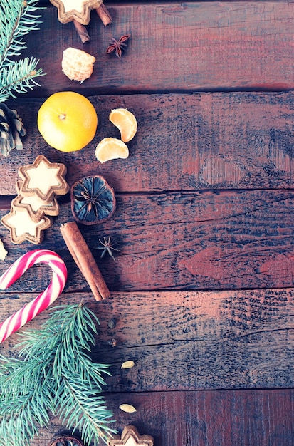 Новогодний фон текстура древесины украшена еловыми ветками, специями, мандаринами и конфетами