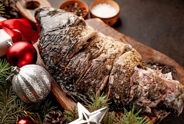 Christmas baked carp on a stone table with trees and toys