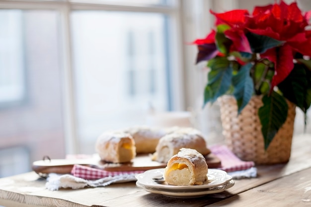 Christmas baked goods on a table near a window and a flower with red leaves