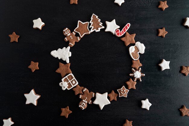 Christmas baked goods top view on black background. Gingerbread glazed painted cookies. Copy space.