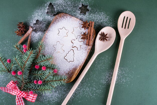 クリスマスのベーキング。まな板の上の装飾、小麦粉、スパイス、クッキー型とモミの木。