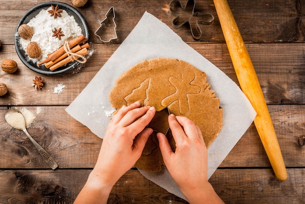 Christmas baking Ginger dough for gingerbread gingerbread men stars Christmas trees rolling pin spices (cinnamon and anise) flour On the home kitchen wooden table