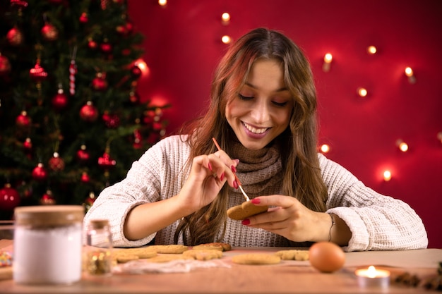 クリスマスのベーキング。大晦日の家族の夕食のためにクリスマスのクッキーデコレーションを作る若いきれいな女性は、家で冬の休日を楽しんでいます。クラフトベーカリーデザート料理、季節の雑用の伝統