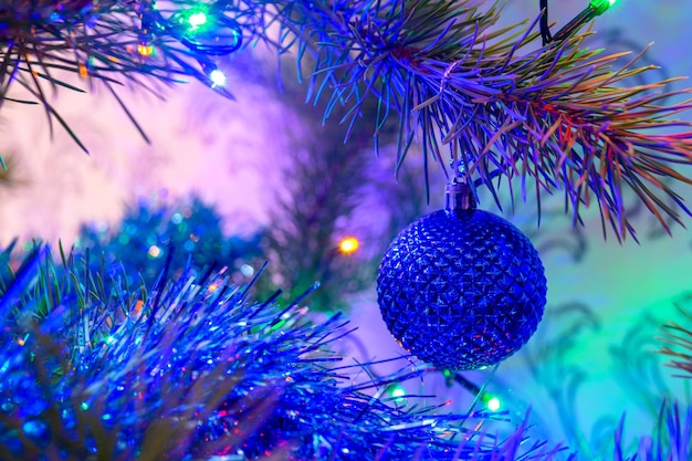 Foto la palla di natale su un albero di natale sullo sfondo di luci sfocate da una ghirlanda