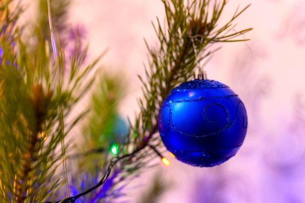 The Christmas ball on a Christmas tree against the background of blurry lights from a garland