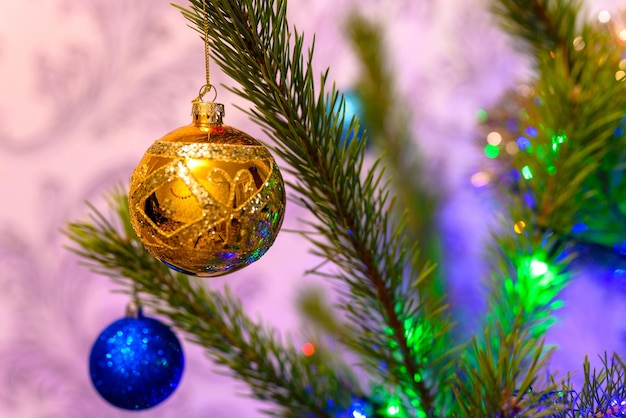 The Christmas ball on a Christmas tree against the background of blurry lights from a garland