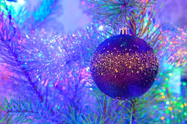 The christmas ball on a christmas tree against the background of blurry lights from a garland