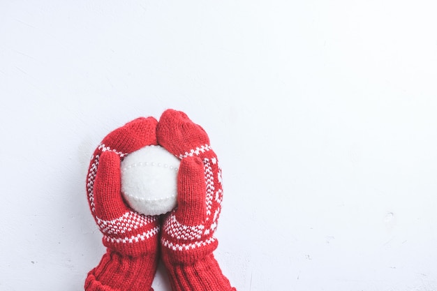 Christmas ball decoration in female hands in knitted mittens