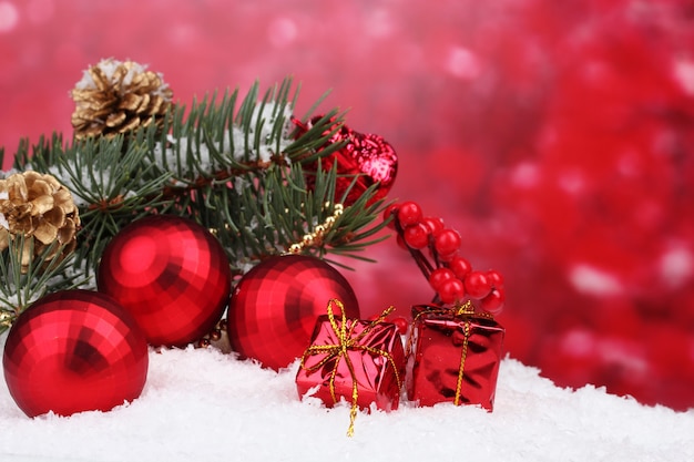 Christmas ball and green tree in the snow on red