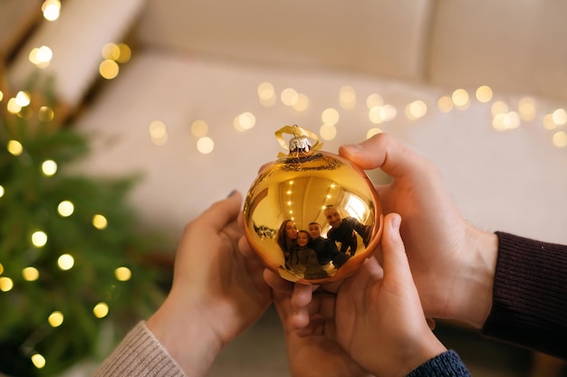 A Christmas ball in hands with reflection of family