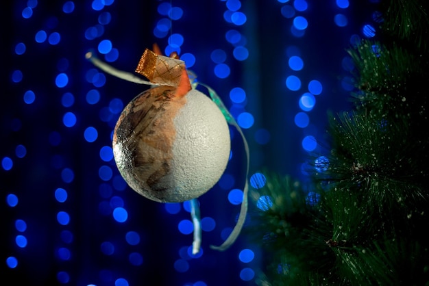 Christmas ball near christmas tree on neon blue background