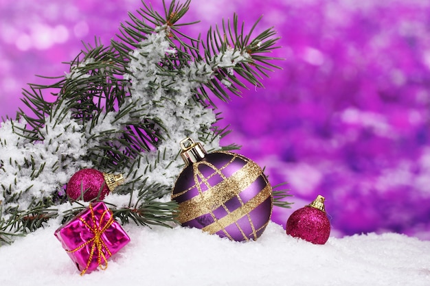 紫の雪の中で緑の木とクリスマスボールとおもちゃ