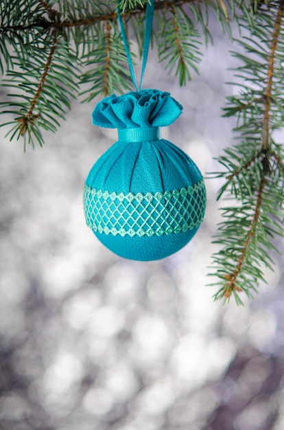 A Christmas ball with a pattern hangs on a fir branch on a silver background. New year decoration.