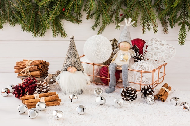 Christmas balls in basket, gnome and angel, Christmas tree on white wooden background