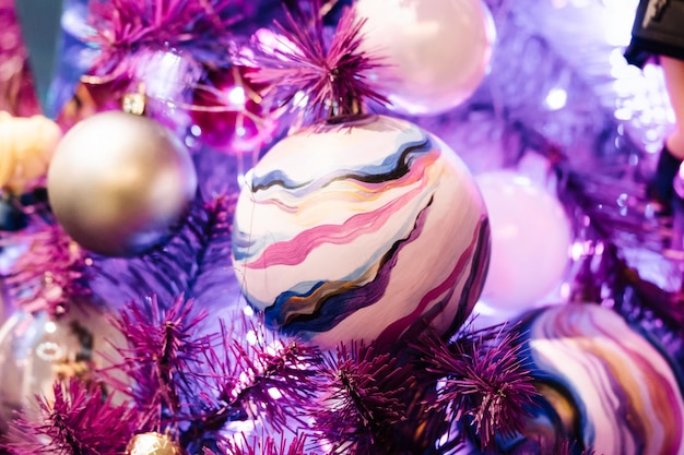 Christmas balls and glowing garlands on a purple christmas tree