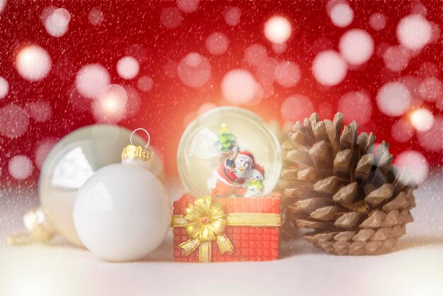 Christmas balls santa claus in a snow globe and pine cones on a creamcolored cloth set against a red background and exquisite bokeh new year celebration atmosphere about of important day