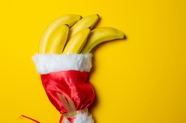 Christmas bananas on yellow background in santa claus cap holiday products concept