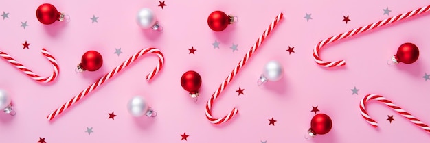 Christmas banner Creative holiday pattern made of candy canes and baubles on pink background