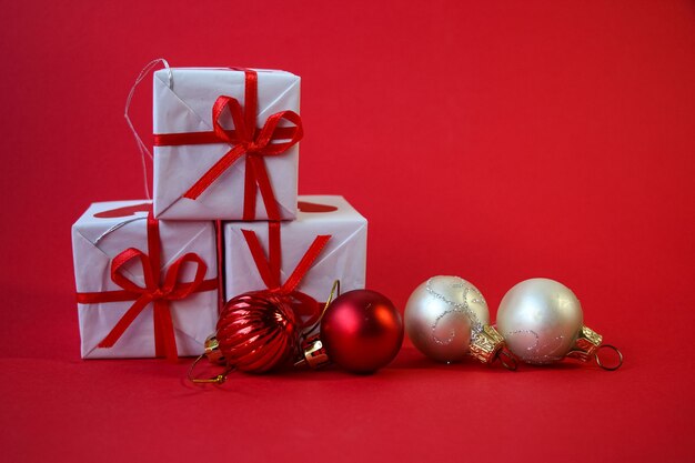 Christmas banner with three white gift boxes and white and red Christmas tree decorations on red