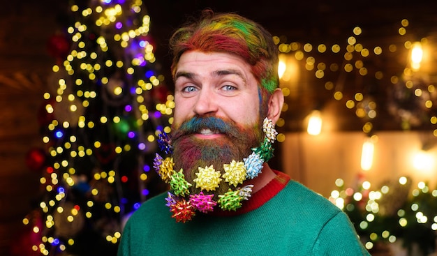 Foto la pubblicità del barbiere di natale di un uomo barbuto sorridente con i capelli colorati e la barba con il natale