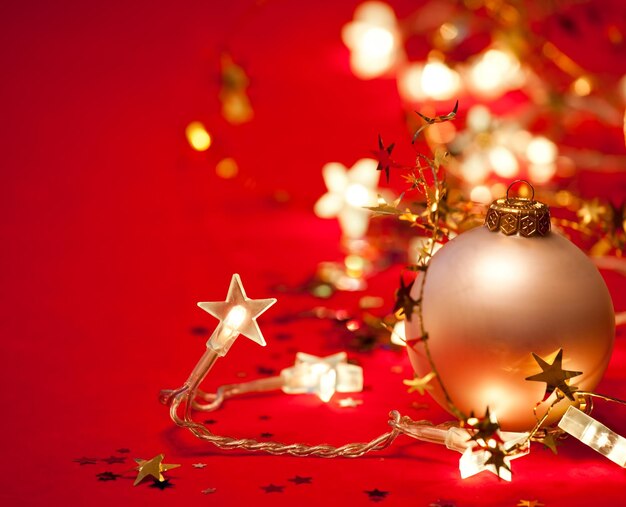 Christmas bauble with starshaped lights and tinsel on red background