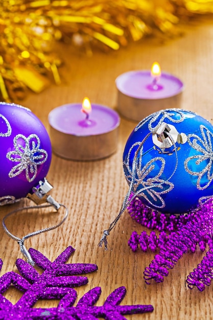 Christmas baubles and glowing candles on wooden boards