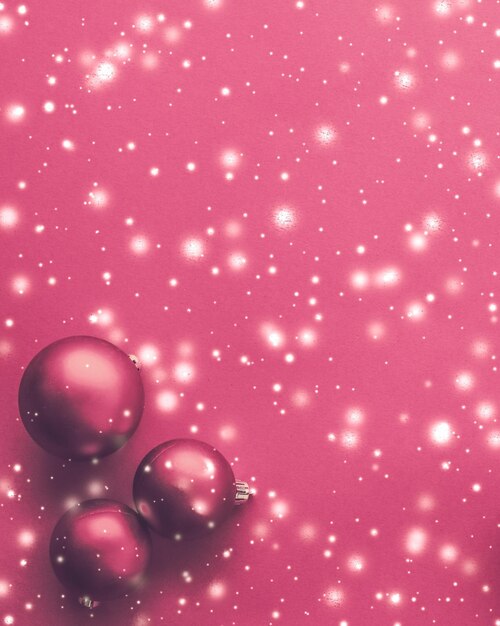 Photo christmas baubles on pink background with snow glitter luxury winter holiday card