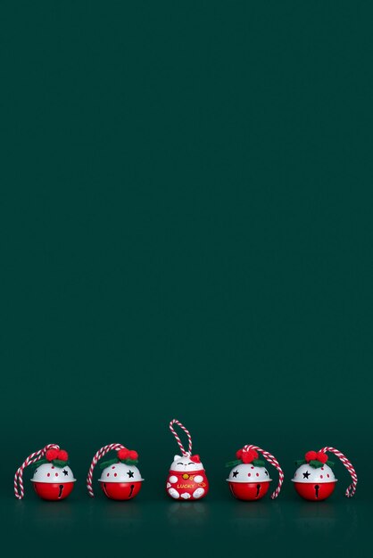 Christmas bells and lucky cat figure in a row on green background with copy space christmas theme