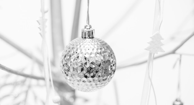 Christmas black and white image with alternative Xmas tree from silver colored wood decorated with Xmas ball close up.