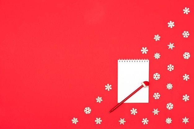 Christmas blank greeting card mockup with pen on red background with white snowflakes Xmas or New Year holiday concept Flat lay style with copy space