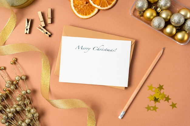 Christmas blank letter with Christmas decoration on beige background. Holiday decorations, gold ribbon, pencil. Eco christmas.