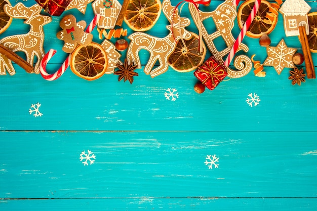 Рождественский синий деревянный фон с пряниками, корицей, апельсином и шариками.