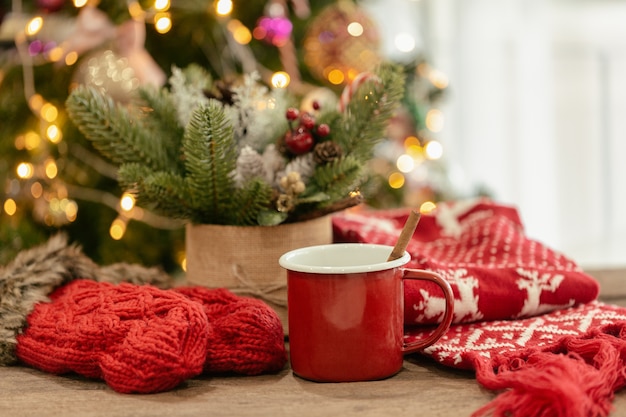 Photo christmas bokeh background with red gloves, red scarf and red cup of hot chocolate on wood table.