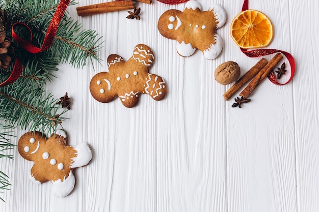 Christmas border. Gingerbread cookies, spices and decorations on white wooden background.