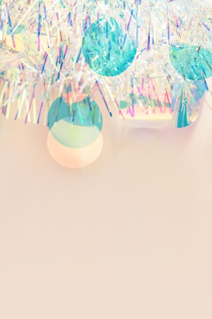 Photo christmas border iridescent tinsel garland on pastel beige background with copy space.