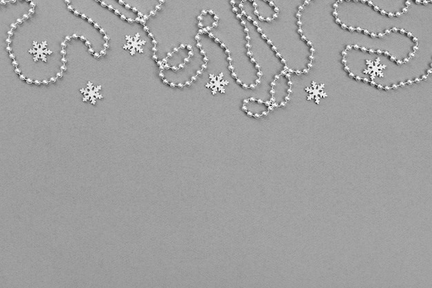 Christmas border with silver snowflakes and garland on grey background.