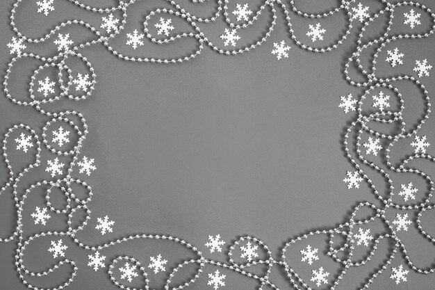 Christmas border with snowflakes and silver garland on grey background.