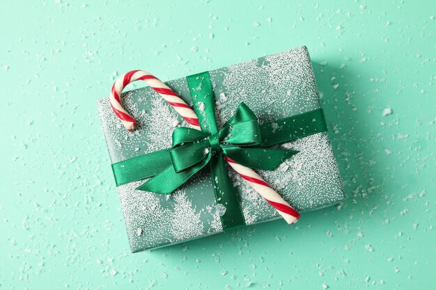 Christmas box with candy cane on mint table with snow