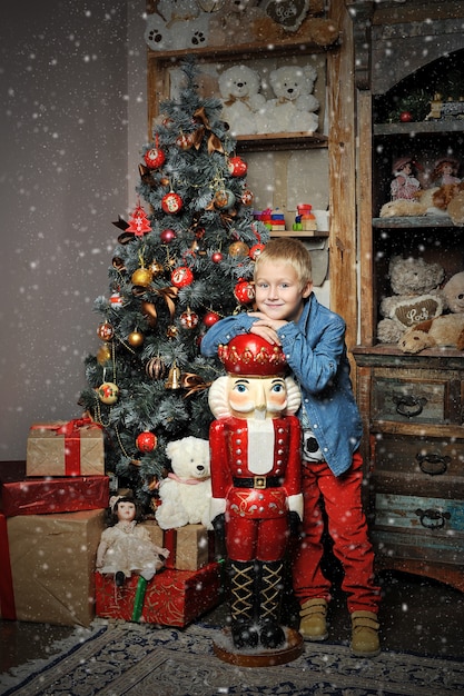 Christmas boy and the Nutcracker around Christmas tree with gifts