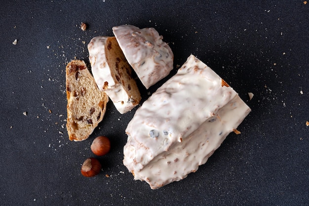 Christmas bread stollen with nuts and dried fruits on a wooden board on a dark background flat lay