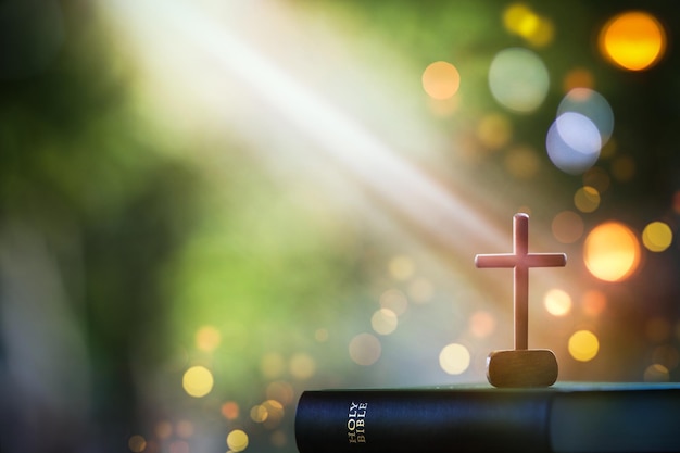 Christmas bright light background with bible and crucifixion of\
jesus christ and lights bokeh backgr