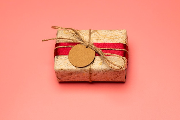 Christmas brown gift boxes and red ribbon with tag paper lay on the pink table, front view with copy space.