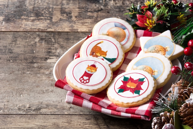 Christmas butter cookies decorated with christmas graphics, on wooden table copyspace